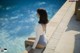 A woman sitting on the edge of a swimming pool.