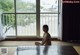 A woman sitting on the floor in front of a large window.