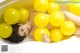 A woman laying in a bathtub filled with yellow balloons.