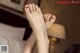 A woman's feet with red nail polish on a bed.
