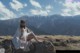 A woman sitting on top of a rock in the mountains.