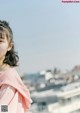 A woman in a pink dress standing on top of a building.